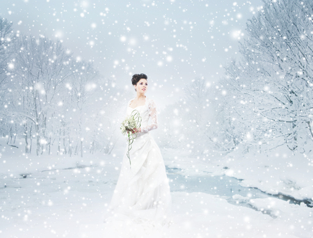 Young and beautiful bride with the flower bouquet in winter forestの写真素材