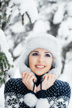 Portrait of young and beautiful girl walking in winter forest. Christmas seasonal concept.