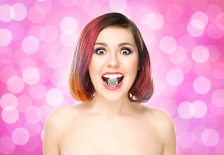 Beautiful girl with colored hair having a jelly in mouth on bubbly background.の写真素材