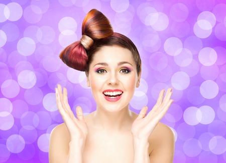 Beautiful smiling girl with a bow haircut and colorful make-up on bubble background.の写真素材