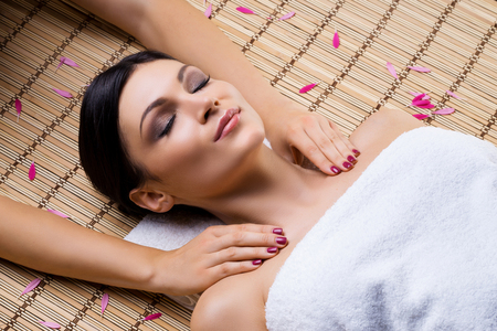 Beautiful, young and healthy woman on bamboo mat in spa salon having shoulders massage. Spa, health and healing concept.の写真素材