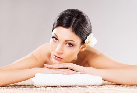 Beautiful, young and healthy woman in spa salon. Massage treatment over grey background. Spa, health and healing concept.の写真素材