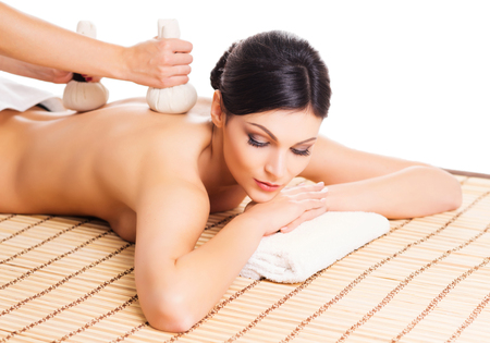 Beautiful, young and healthy woman on bamboo mat in spa salon is having massage. Isolated on white. Spa, health and healing concept.の写真素材