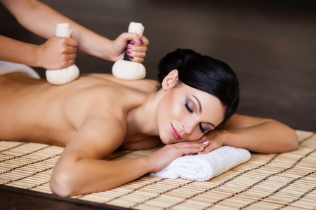 Beautiful, young and healthy woman on bamboo mat in spa salon is having massage. Spa, health and healing concept.の写真素材
