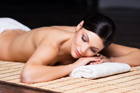 Beautiful, young and healthy woman in spa salon. Massage treatment over black background. Spa, health and healing concept.の写真素材