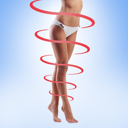 Close-up of thin and beautiful female body. Weight loss, fat burn, sports, exercising concept. Red arrows.の写真素材