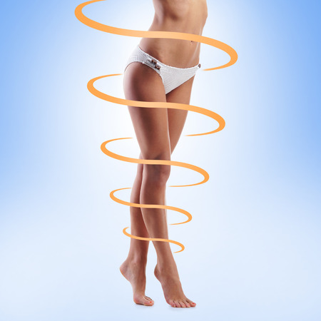 Close-up of thin and beautiful female body over blue background. Weight loss, sports, exercising, tan, sun burn concept.の写真素材
