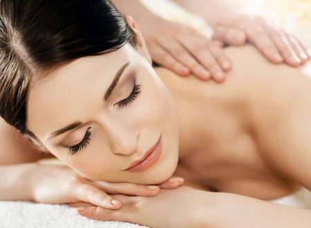 Young and beautiful girl relaxing in Christmas spa salon. Massage therapy, healing medicine and health care concept.の写真素材