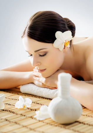 Young and beautiful girl relaxing in Christmas spa salon. Massage therapy, healing medicine and health care concept.の写真素材