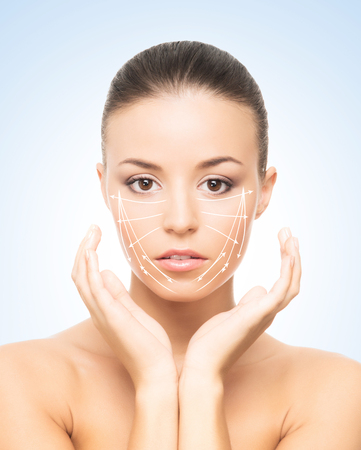 Portrait of beautiful, young woman with a perfect skin and arrows on her face. Face lifting, make-up, plastic surgery and skin care concept.の写真素材