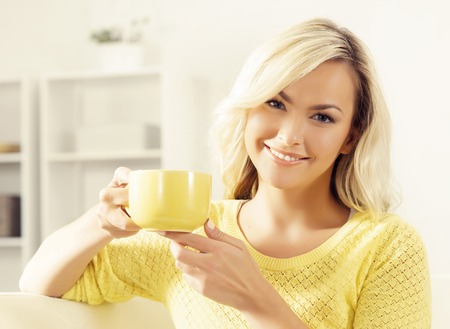 Attractive happy girl with a cup of coffee at home.の写真素材
