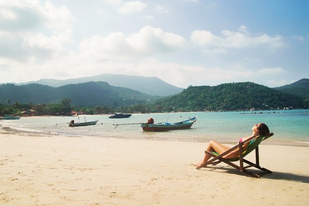 Beautiful, fit woman sunbathing in the deckchair and having a recreation on the beach in Thailand.の写真素材