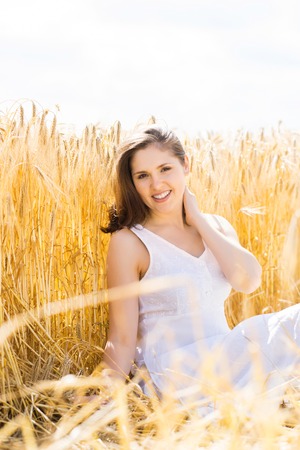 Young, emotional and happy woman in a meadow of rye. Beautiful girl in a white dress. Summer concept.の写真素材