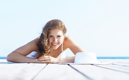 Woman in white dress on a wooden pier on summer.  Sea and sky background. Vacation, traveling and freedom concept.の写真素材