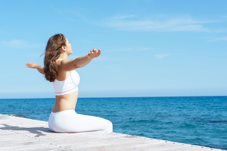 Woman in white dress on a wooden pier on summer.  Sea and sky background. Vacation, traveling and freedom concept.の写真素材