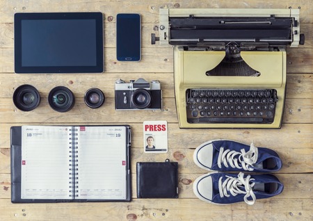 Journalistic equipment: typewriter, tablet, phone, camera, lenses, album, glasses and different objects. Past and nowadays concept. Freelancers outfit.の写真素材