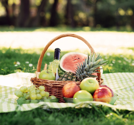 Basket full of fruits on a mat in the park.の写真素材