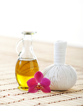 Orchid, jar with oil and massaging ball on woven bamboo mat over isolated background.の写真素材