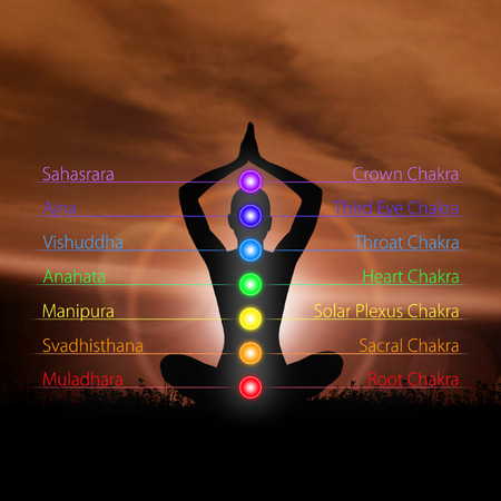 Silhouette of monk meditating in lotus position. Colored chakra lights over body. Yoga, zen, Buddhism, recovery, religion and wellbeing concept.の写真素材