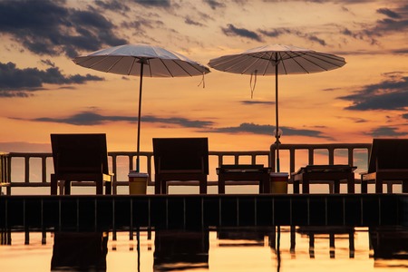 Terrace with a view on sea and sunset. Umbrellas and lounge chair in a sunlight.の写真素材