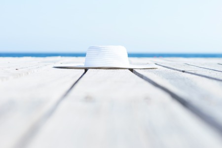 White hat on a wooden pier on summer.  Sea and sky background. Vacation, traveling and freedom concept.の写真素材