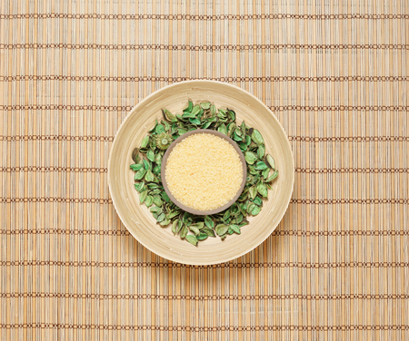 Plate with bath salt on green leaves over bamboo mat. Spa, health, treatment concept.の写真素材