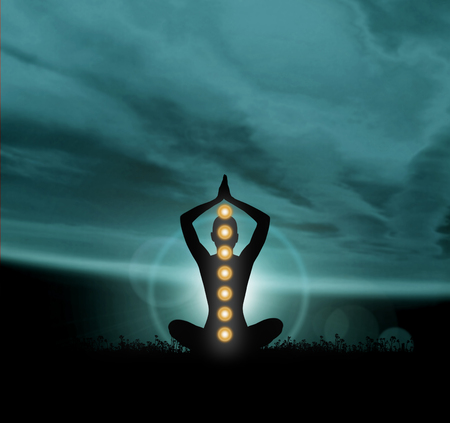 Silhouette trace of human meditating in lotus position. Colored chakra lights over body. Yoga, zen, Buddhism, recovery, religion, healthcare and wellbeing concept.の写真素材