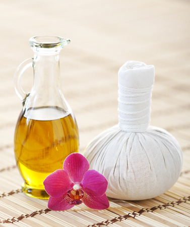 Orchid, jar with oil and massaging ball on woven bamboo mat over isolated background.の写真素材