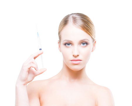 Young woman holding a syringe in her hands and injecting botox into smooth skin.の写真素材