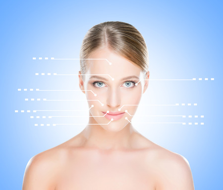 Spa portrait of a young and healthy woman with arrows on her face pointing on a face areas. Plastic surgery concept.の写真素材