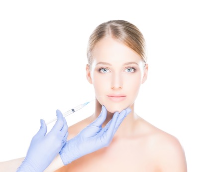 Doctor injecting in a beautiful face of a young woman. Plastic surgery concept.の写真素材