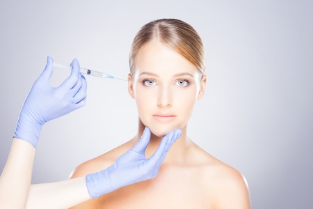 Doctor injecting in a beautiful face of a young woman. Plastic surgery concept.の写真素材