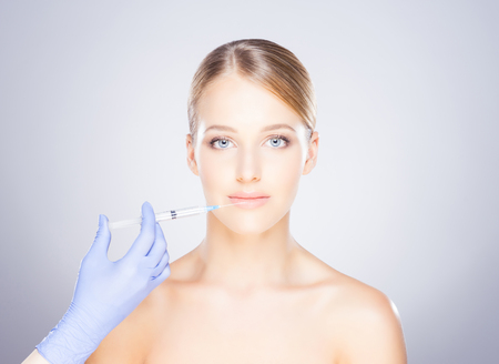 Doctor injecting in a beautiful face of a young woman. Plastic surgery concept.の写真素材