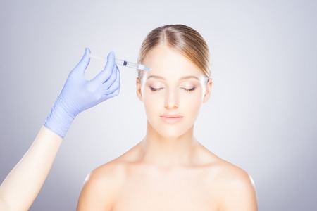Doctor injecting in a beautiful face of a young woman. Plastic surgery concept.の写真素材