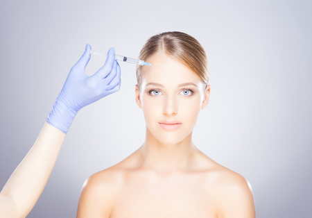 Doctor injecting in a beautiful face of a young woman. Plastic surgery concept.の写真素材
