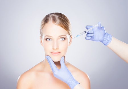 Doctor injecting in a beautiful face of a young woman. Plastic surgery concept.の写真素材