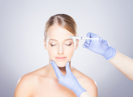 Doctor injecting in a beautiful face of a young woman. Plastic surgery concept.の写真素材