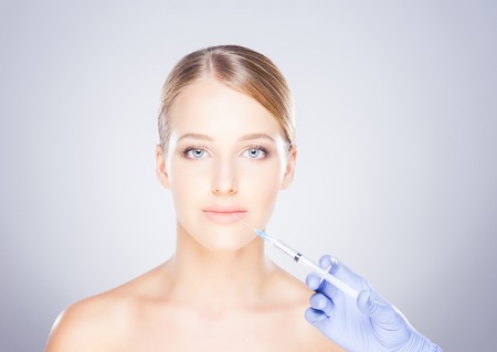 Doctor injecting in a beautiful face of a young woman. Plastic surgery concept.の写真素材