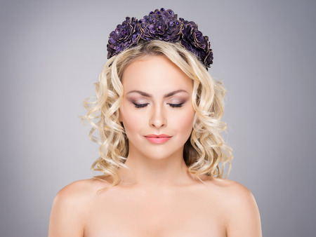 Gorgeous blond with closed eyes wearing purple flower alike crown over grey background.の写真素材