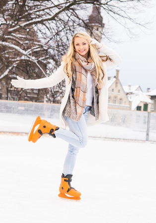 Young and pretty girl skating on outdoor open air ice-rink at winter.の写真素材