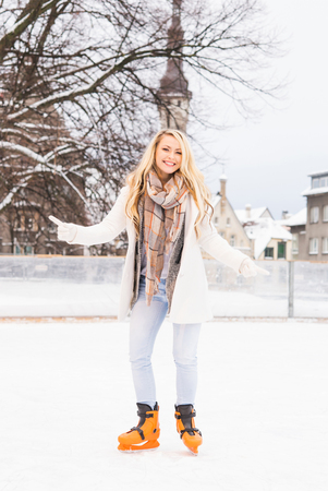 Young and pretty girl skating on outdoor open air ice-rink at winter.の写真素材