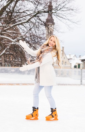 Young and pretty girl skating on outdoor open air ice-rink at winter.の写真素材