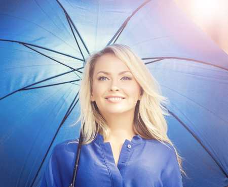 Beautiful young woman with blue umbrella in city center. Attractive woman in the street.の写真素材