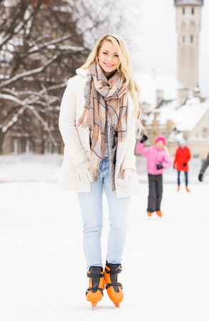 Young and pretty girl skating on outdoor open air ice-rink at winter.の写真素材