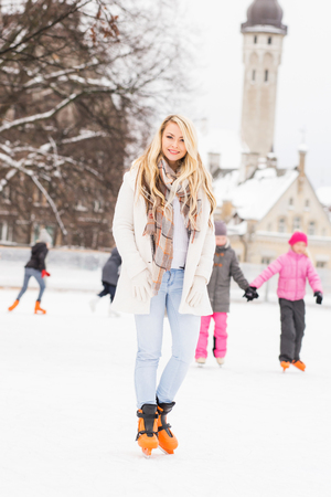 Young and pretty girl skating on outdoor open air ice-rink at winter.の写真素材