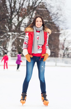 Young and pretty girl skating on outdoor open air ice-rink at winter.の写真素材