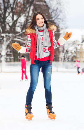Young and pretty girl skating on outdoor open air ice-rink at winter.の写真素材