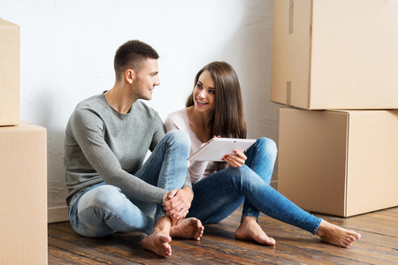 Young couple moving in a new home. Man and woman with a tablet computer and boxes.の写真素材