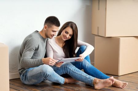 Young couple moving in a new home. Man and woman with a tablet computer and boxes.の写真素材