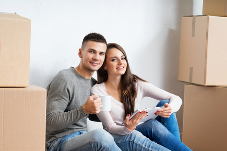 Young couple moving in a new home. Man and woman with a tablet computer and boxes.の写真素材